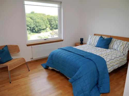Un dormitorio con una cama azul y una ventana. en Annapurna, en Portpatrick