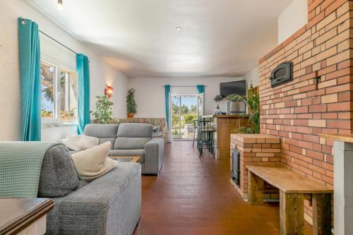 a living room with a couch and a brick wall at Arrifana Pines in Aljezur