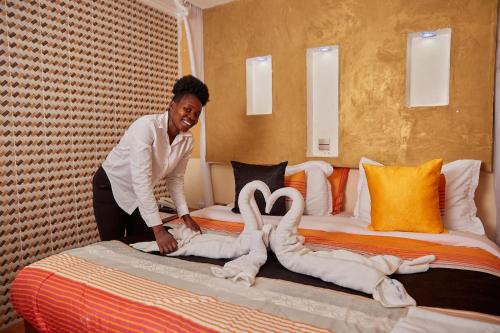 a woman making a bed with swans made out of towels at Dunga LakeSide Resort in Kisumu