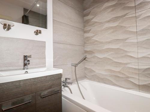 a bathroom with a sink and a tub and a shower at 6 Ocean Heights in Newquay