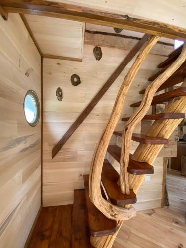 a spiral staircase in a log cabin with wooden walls at Les Cabanes De Pyrene in Cazarilh