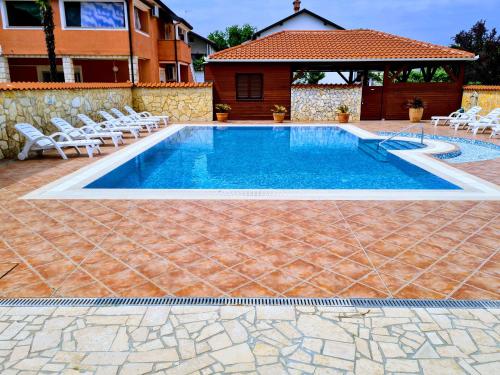 a swimming pool with chairs and a house at Villa Bonaca in Umag