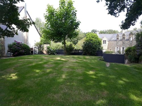 a large yard with a tree in the middle of it at Paradis pour les petits, quiétude pour les grands. in Brech