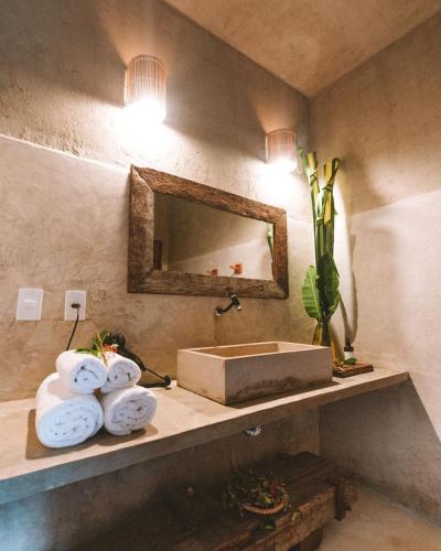 a bathroom with a sink and a mirror and towels at Pousada Haya in São Miguel dos Milagres