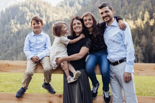a family posing for a picture on a fence at Alpine Chalet Sauter in San Vigilio Di Marebbe