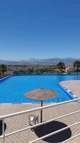a large swimming pool with a straw umbrella at Apartement cabo in Tétouan