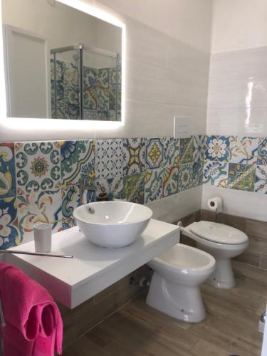 een badkamer met een wastafel, een toilet en een spiegel bij Casa il Tramonto del Cilento in Scario