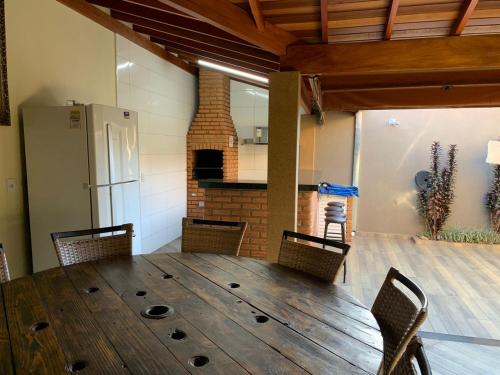 a room with a wooden table with chairs and a refrigerator at Casa Thermas Olimpia I - 150 metros do Thermas dos Laranjais in Olímpia