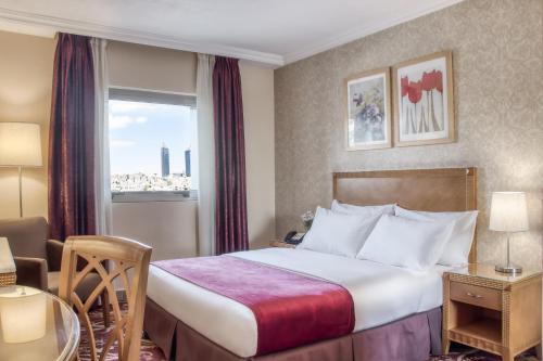 pokój hotelowy z łóżkiem i oknem w obiekcie Geneva Hotel w mieście Amman
