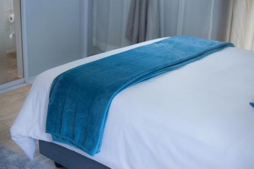 a bed with a blue blanket on top of it at Kv Luxury Guest House in Johannesburg