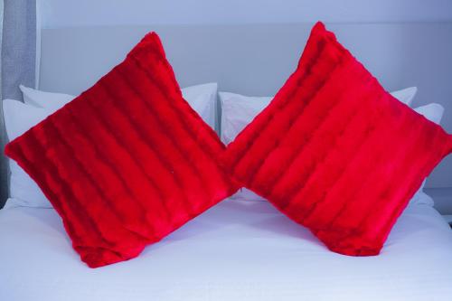 two red pillows sitting on top of a bed at Kv Luxury Guest House in Johannesburg