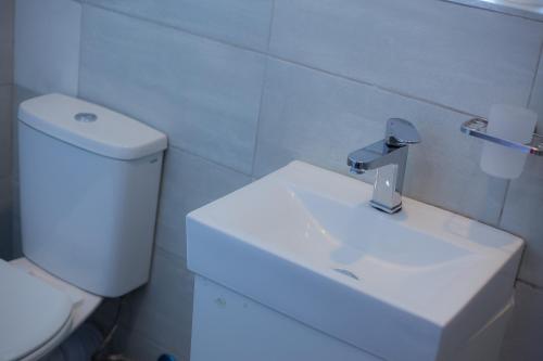 a bathroom with a white sink and a toilet at Kv Luxury Guest House in Johannesburg