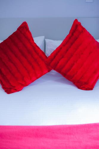 a pair of red pillows on a white bed at Kv Luxury Guest House in Johannesburg