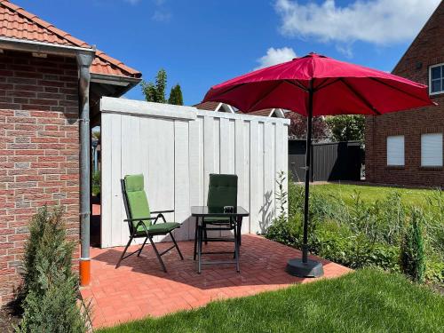 two chairs and a table with a red umbrella at Marions Apartments Greetsiel in Greetsiel
