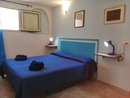 a bedroom with a blue bed with two black hats on it at Appartamenti le conchiglie e le Stelle Marine in Cala Gonone