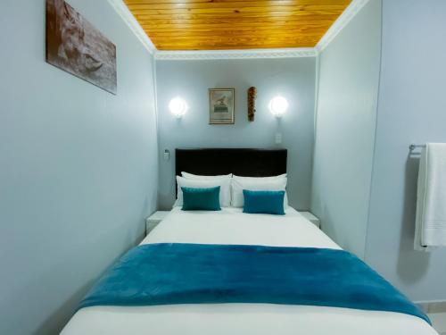 a bedroom with a large bed with blue pillows at Kv Luxury Guest House in Johannesburg