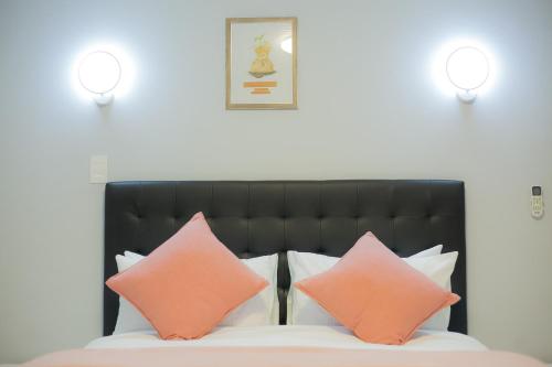 a bed with pink and orange pillows on it at Kv Luxury Guest House in Johannesburg