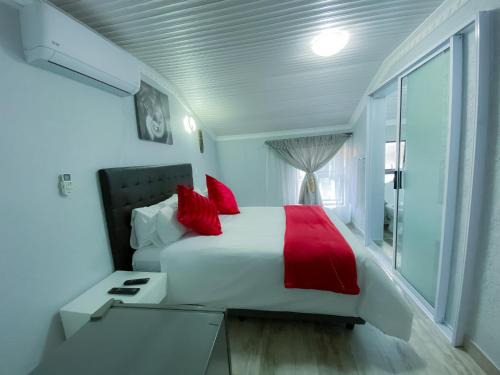 a bedroom with a white bed with red pillows at Kv Luxury Guest House in Johannesburg