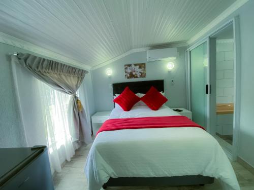 a bedroom with a large white bed with red pillows at Kv Luxury Guest House in Johannesburg
