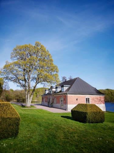 een groot rood bakstenen huis met een boom in de tuin bij The Norrmans Castle in Genarp