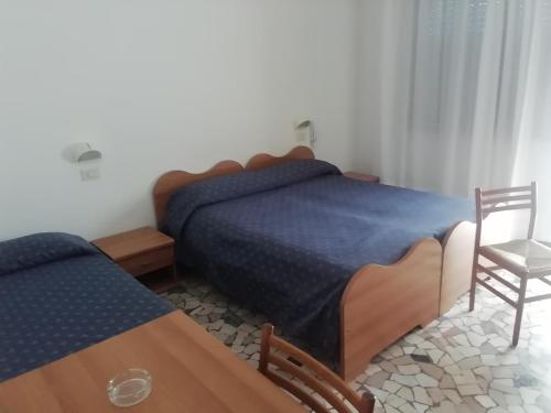 - une chambre avec deux lits, une table et une chaise dans l'établissement Lorena, à Sottomarina
