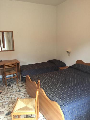 Cette chambre comprend deux lits, une table et un bureau. dans l'établissement Lorena, à Sottomarina