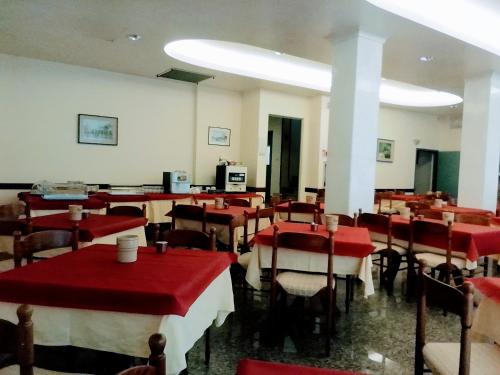 un restaurant avec des tables, des chaises et des nappes rouges dans l'établissement Lorena, à Sottomarina