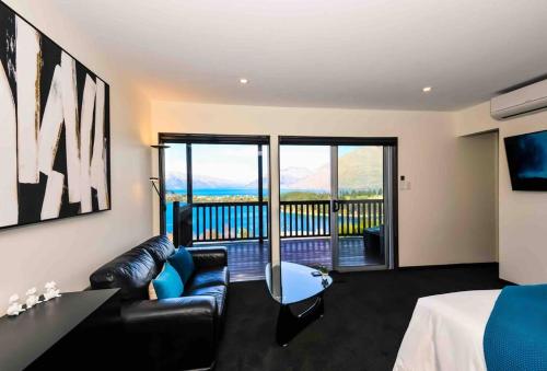 a room with a bed and a couch and a balcony at Lovely Apartment- Amazing Lake & Mountain Views in Queenstown