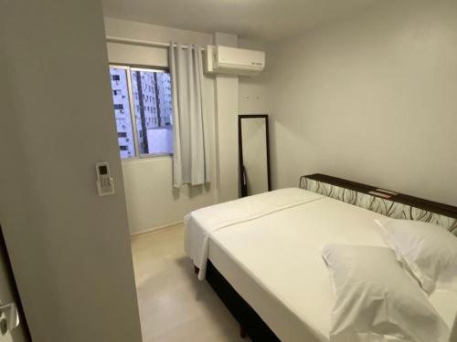 una camera con un letto bianco e una finestra di Quadra do Mar Balneário Camboriú a Balneário Camboriú