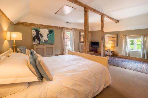 a bedroom with a large white bed in a room at Stylish luxury cottage in historic country estate - Belchamp Hall Coach House in Sudbury