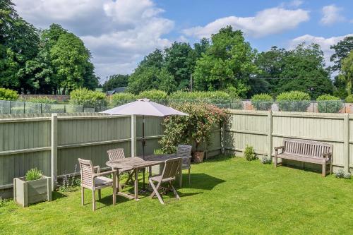 a backyard with a table and chairs and an umbrella at Stylish luxury cottage in historic country estate - Belchamp Hall Coach House in Sudbury