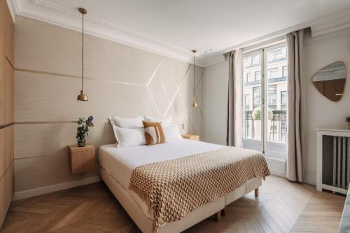 une chambre avec un lit et une grande fenêtre dans l'établissement HIGHSTAY - Luxury Serviced Apartments - Rue de Rivoli, à Paris