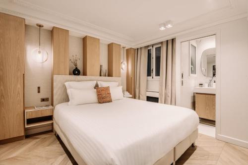 a bedroom with a large white bed and a bathroom at HIGHSTAY - Luxury Serviced Apartments - Louvre-Rivoli in Paris