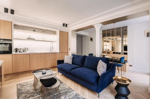 a living room with a blue couch and a kitchen at HIGHSTAY - Luxury Serviced Apartments - Louvre-Rivoli Area in Paris