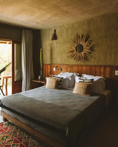 a bedroom with a bed and a mirror on the wall at Pousada Haya in São Miguel dos Milagres