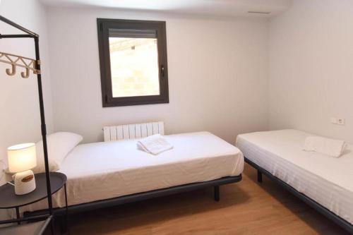 a room with two beds and a table and a window at APG Girona Carme 19 in Girona