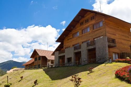 a large wooden building on a hill with flowers at Fazenda Suica Le Canton in Teresópolis