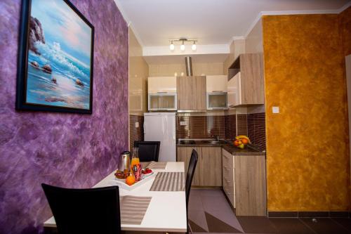 a kitchen with a table and a purple wall at SunSea Apartments in Budva