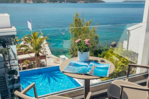a table on a balcony with a view of the ocean at Hotel Perla in Herceg-Novi