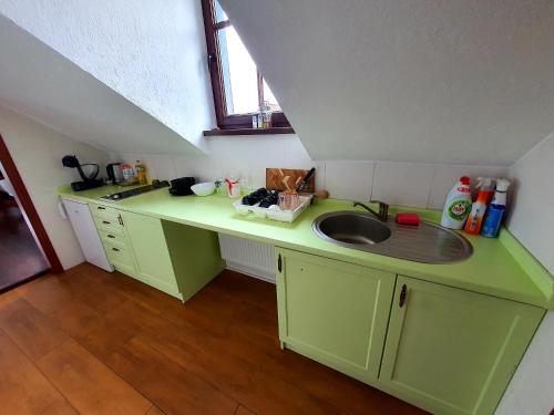 a green kitchen with a sink and a counter at Suite Loft in Zabierzów