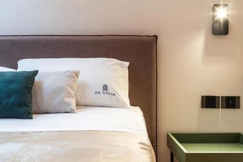 a bed with white pillows and a green end table at De Gulia Charme and Relax in Castellabate