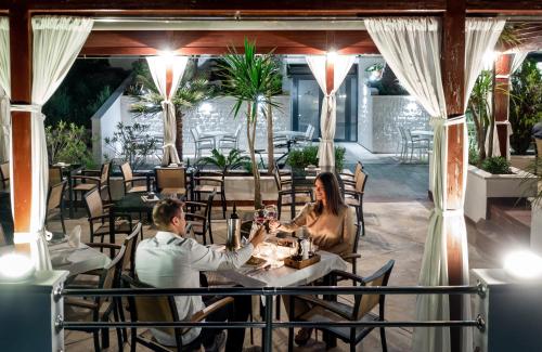 a man and woman sitting at a table in a restaurant at Hotel Perla in Herceg-Novi