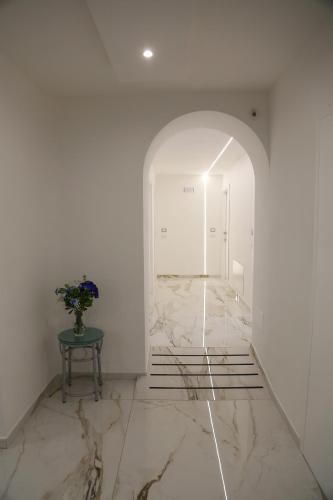 a hallway with white walls and a marble floor with a table at M'incanto B&B in Naples