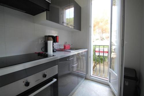 une cuisine avec des comptoirs blancs, une fenêtre et un plan de travail dans l'établissement Argelès-sur-mer, Superbe Appartement de 34 m2 à 50 m de la plage d'Argelès Appartement à Argeles sur mer, à Plage dʼArgelès