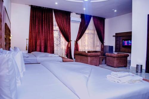 a hotel room with a bed and chairs and curtains at CRISPAN SUITES & EVENT CENTRE in Jos