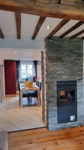 a living room with a stone fireplace and a table at Le Gai Pinson in Beausaint