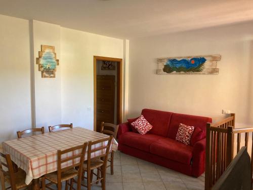 sala de estar con sofá rojo y mesa en Parco Vacanze La Rosa dei Venti, en Marina di Bibbona