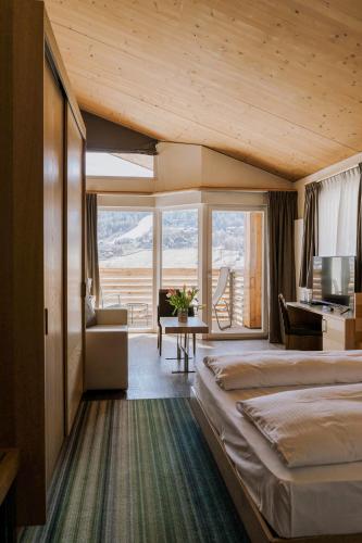 a hotel room with a large bed and a desk at Hotel Lac Salin Spa & Mountain Resort in Livigno