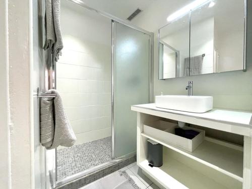 a white bathroom with a sink and a shower at Cosy T2 Saint Martin Vésubie in Saint-Martin-Vésubie