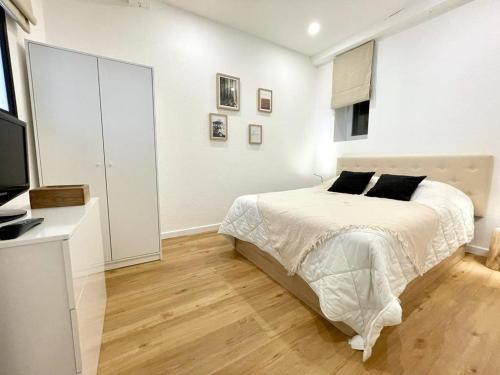 ein weißes Schlafzimmer mit einem Bett und einem TV in der Unterkunft Cosy T2 Saint Martin Vésubie in Saint-Martin-Vésubie
